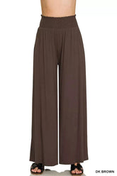 Woman wearing smocked waist wide leg palazzo pants with pockets in a relaxed, flowy style