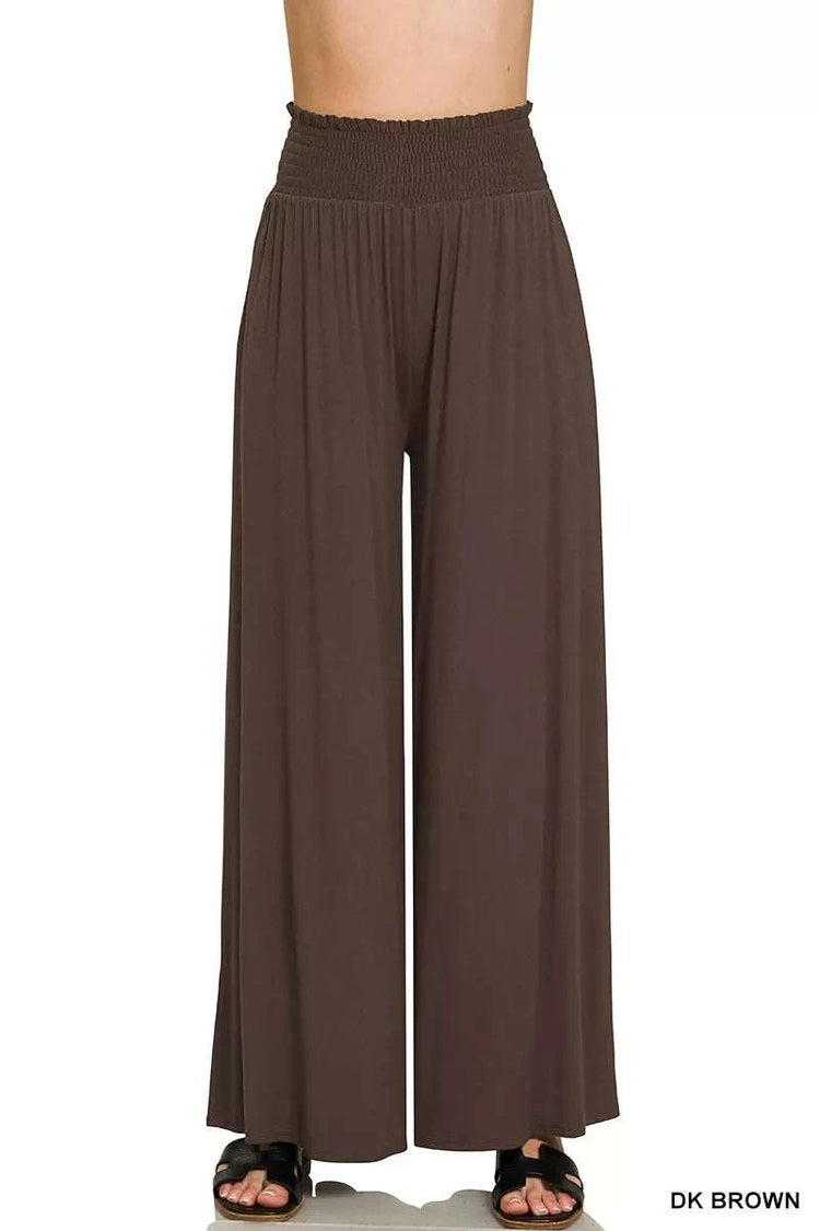 Woman wearing smocked waist wide leg palazzo pants with pockets in a relaxed, flowy style